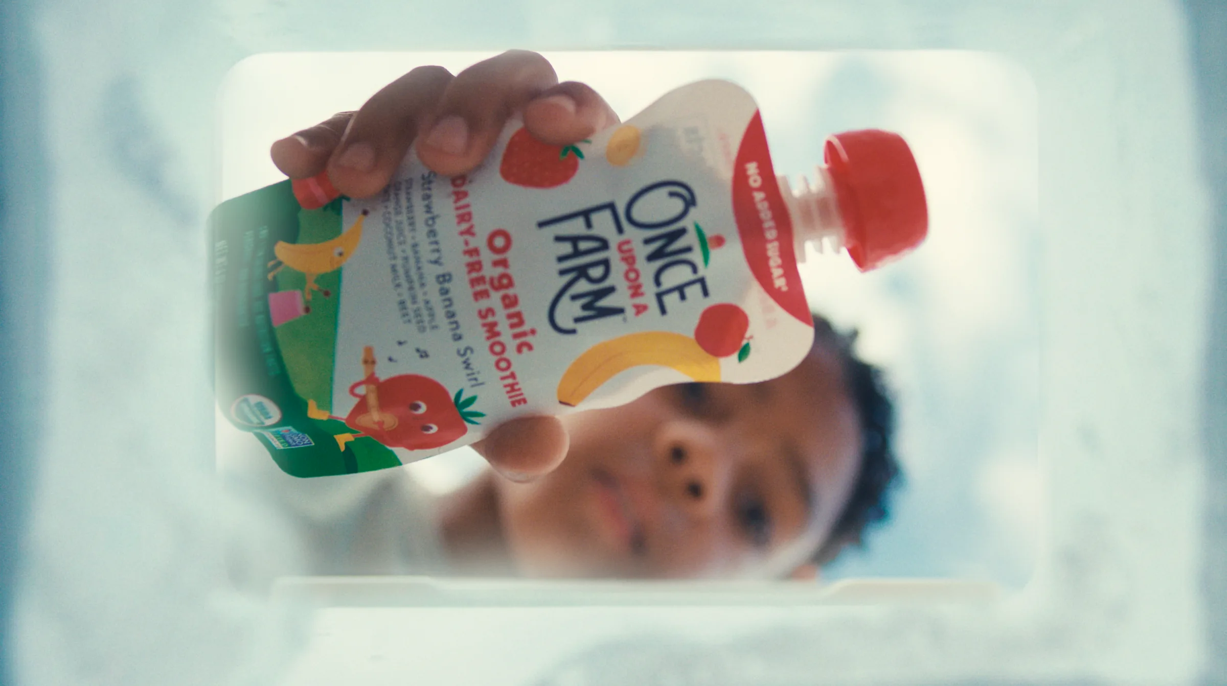 Child reaching for a Once Upon a Farm smoothie pouch