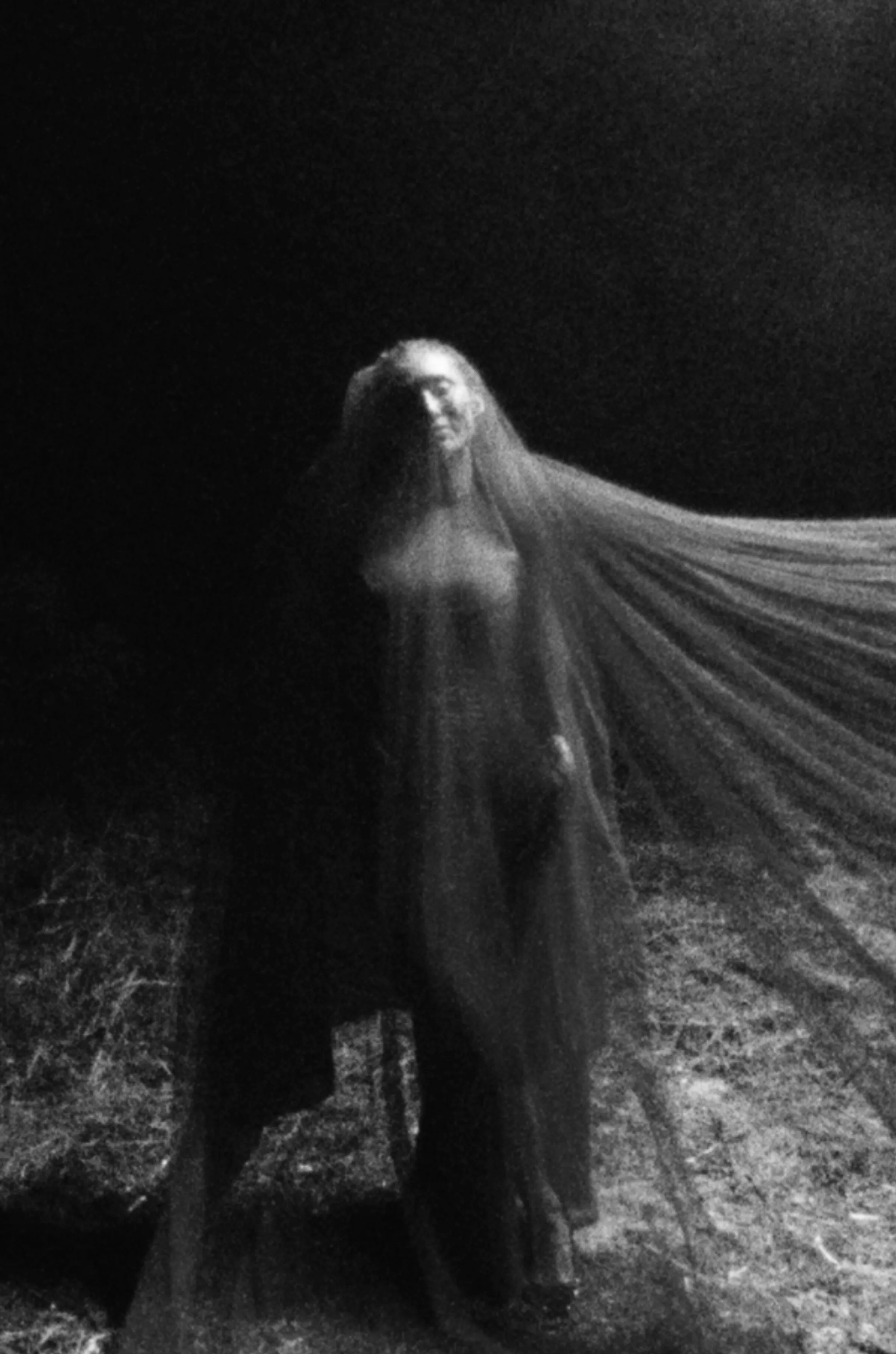 Monochrome figure beneath flowing fabric