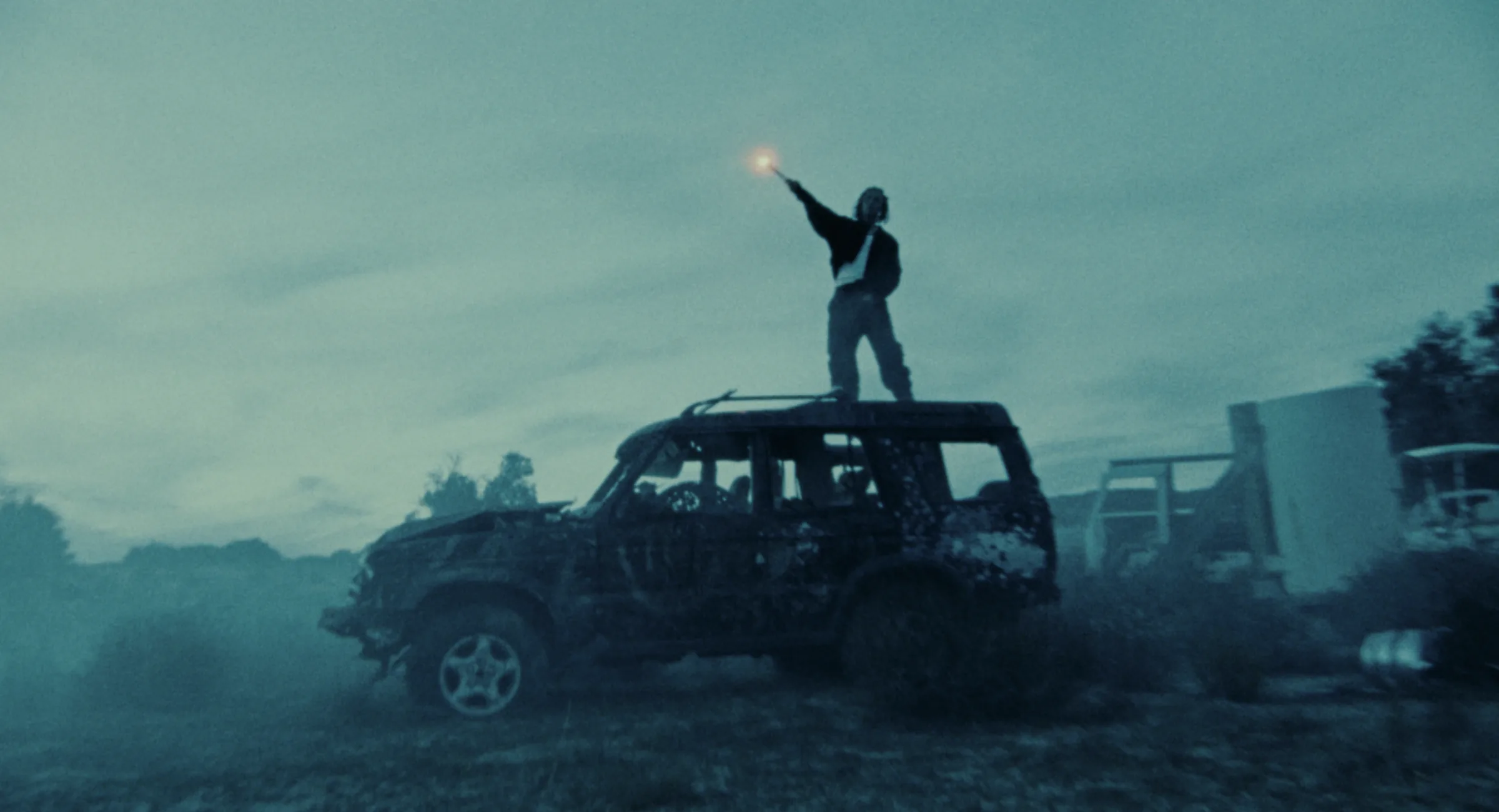 Performer standing on a weathered car at blue hour