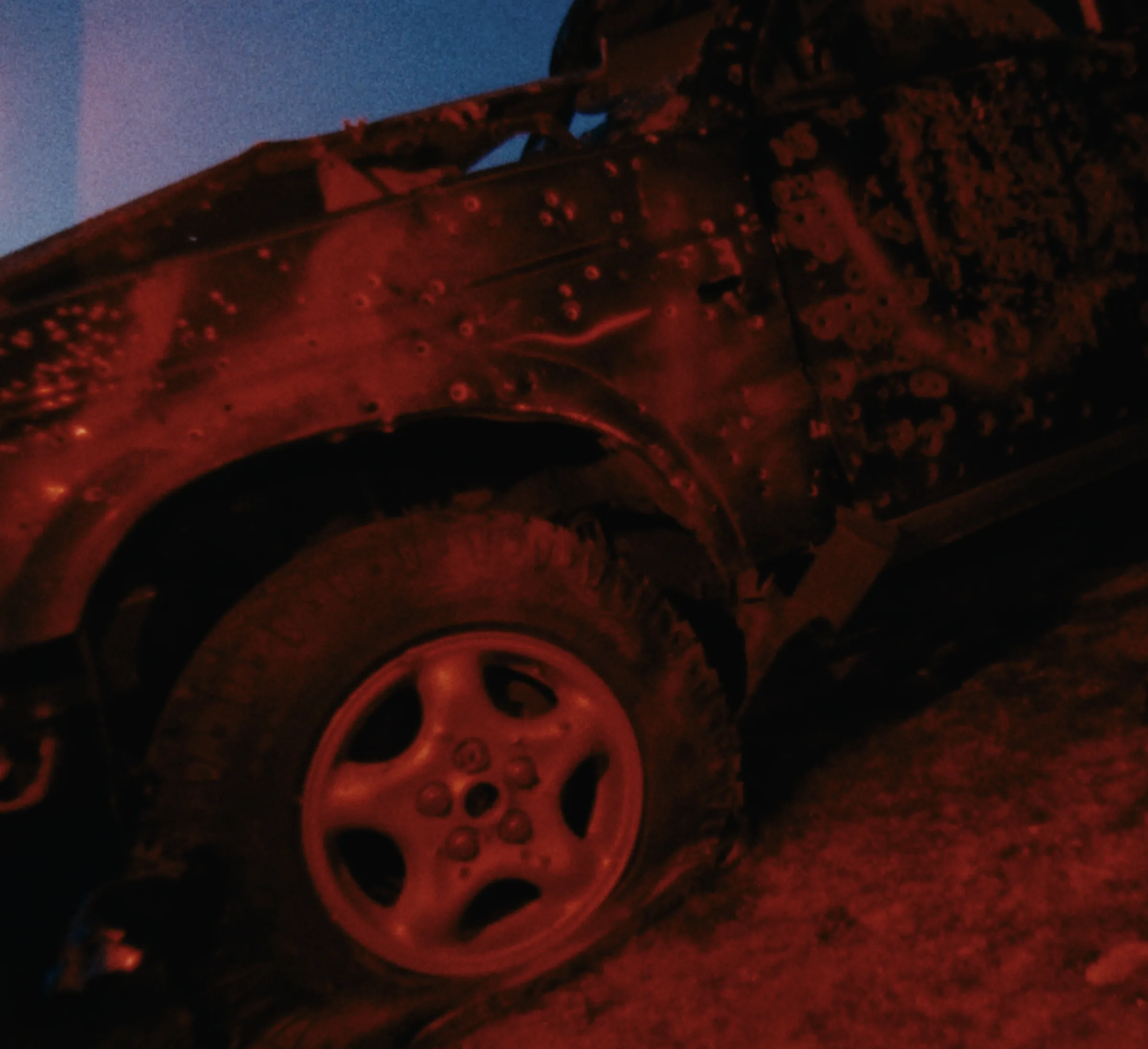 Red-lit detail of a weathered car