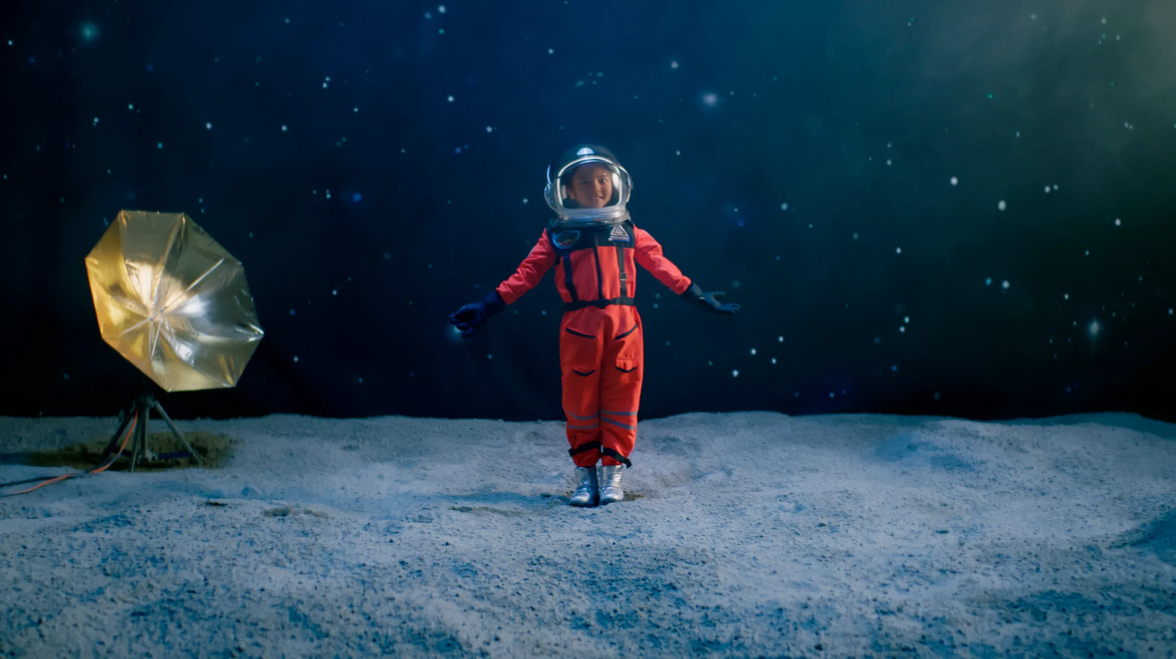 Child astronaut on a moon set beneath a star field
